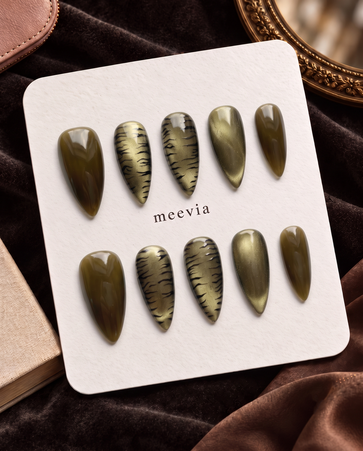 Olive cat-eye and black tiger-print press-on nails displayed on a white card