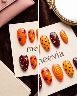Orange and maroon celestial press-on nails with stars, dots, and swirl designs