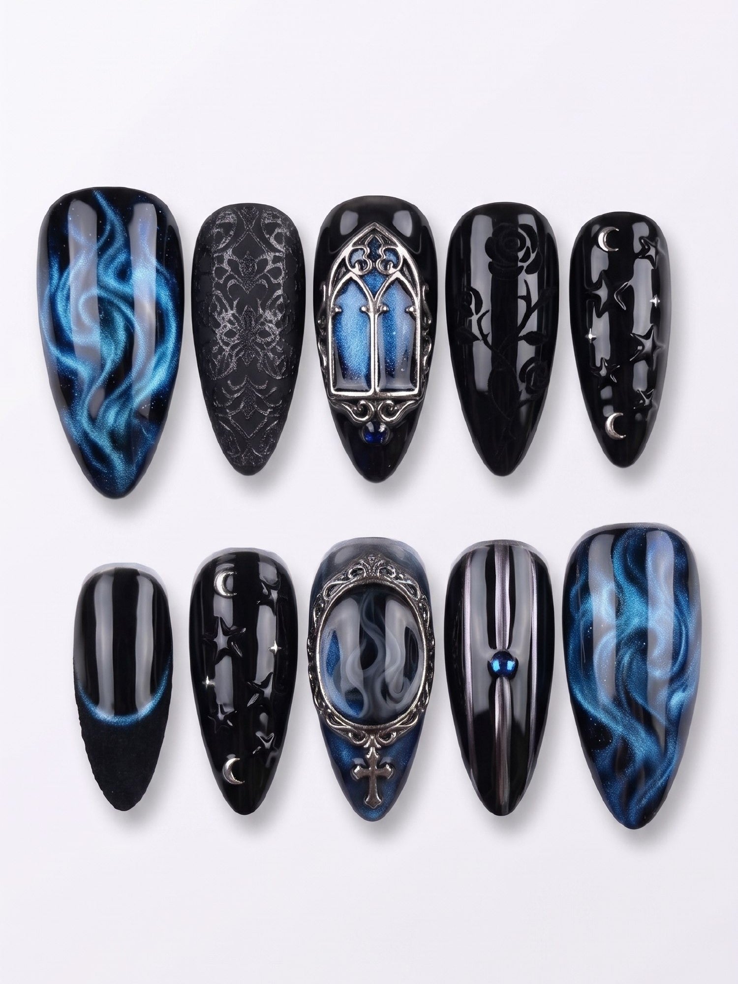 A set of gothic-style press-on nails featuring black and blue smoke patterns, silver cathedral charms, and celestial motifs.