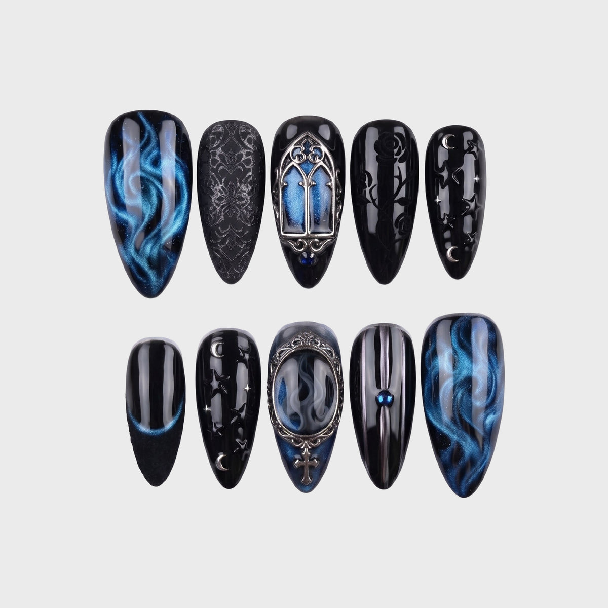 A set of gothic-style press-on nails featuring black and blue smoke patterns, silver cathedral charms, and celestial motifs.