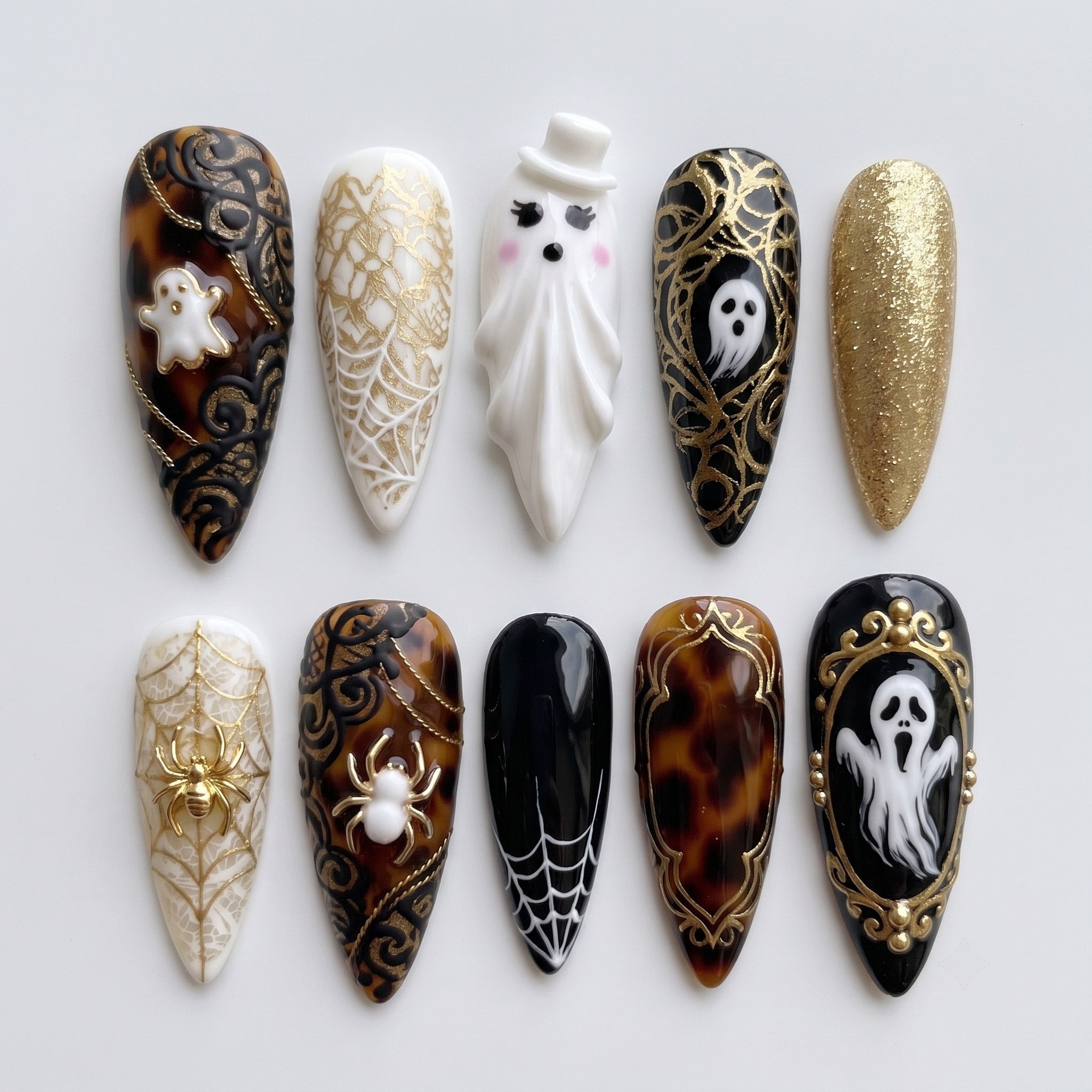 A set of gothic-themed press-on nails featuring ghosts, spiders, tortoiseshell patterns, and gold filigree designs.