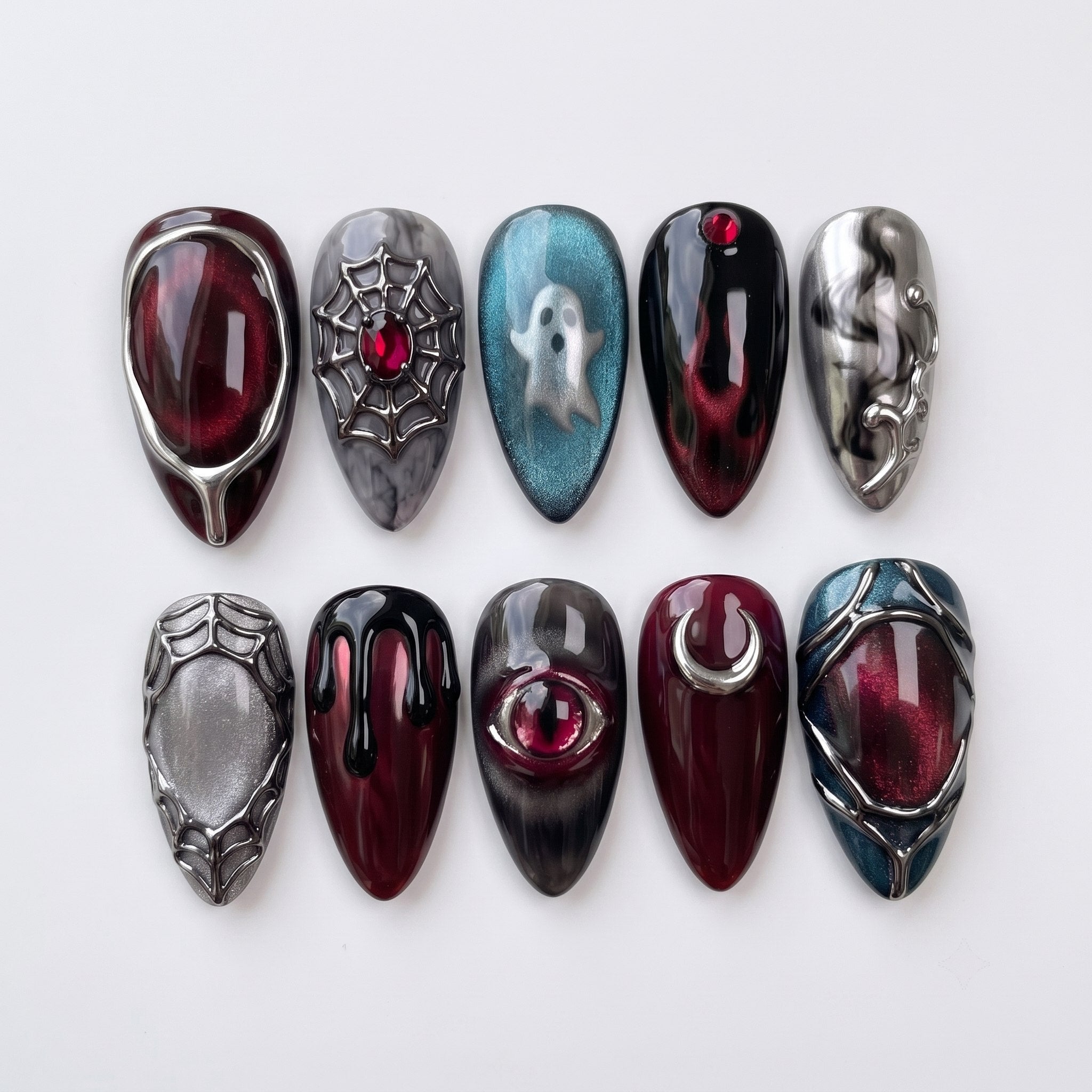 A set of gothic-themed press-on nails featuring a red eye, a silver ghost, spiderwebs, and a crescent moon with 3D metallic accents.