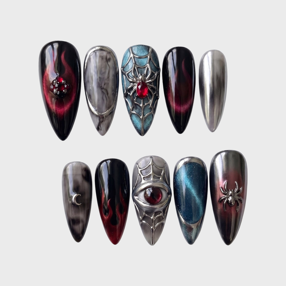 A set of gothic press-on nails featuring spider web designs, chrome finishes, and red crystal embellishments.