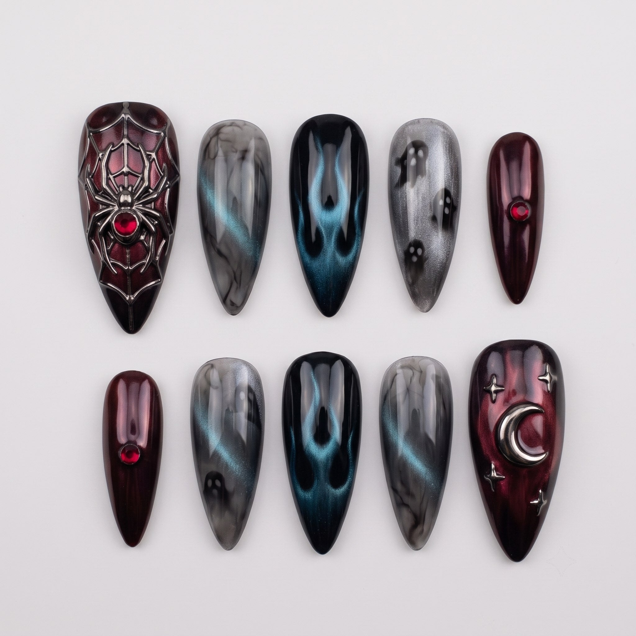 A set of gothic-themed stiletto press-on nails featuring spider webs, ghosts, flames, and moon charms in burgundy and grey tones.