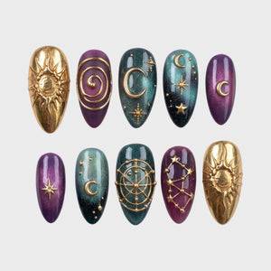 Celestial press-on nails with purple and teal ombre colors and gold sun, moon, and star motifs.