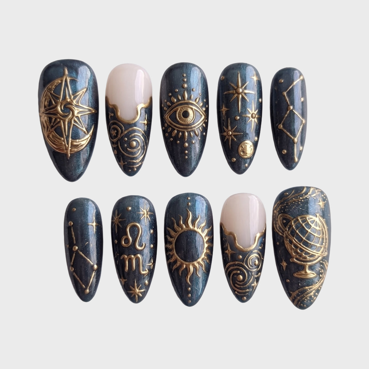 Celestial gold astrology press-on nails featuring sun, moon, and constellation designs on a dark pearlescent base.