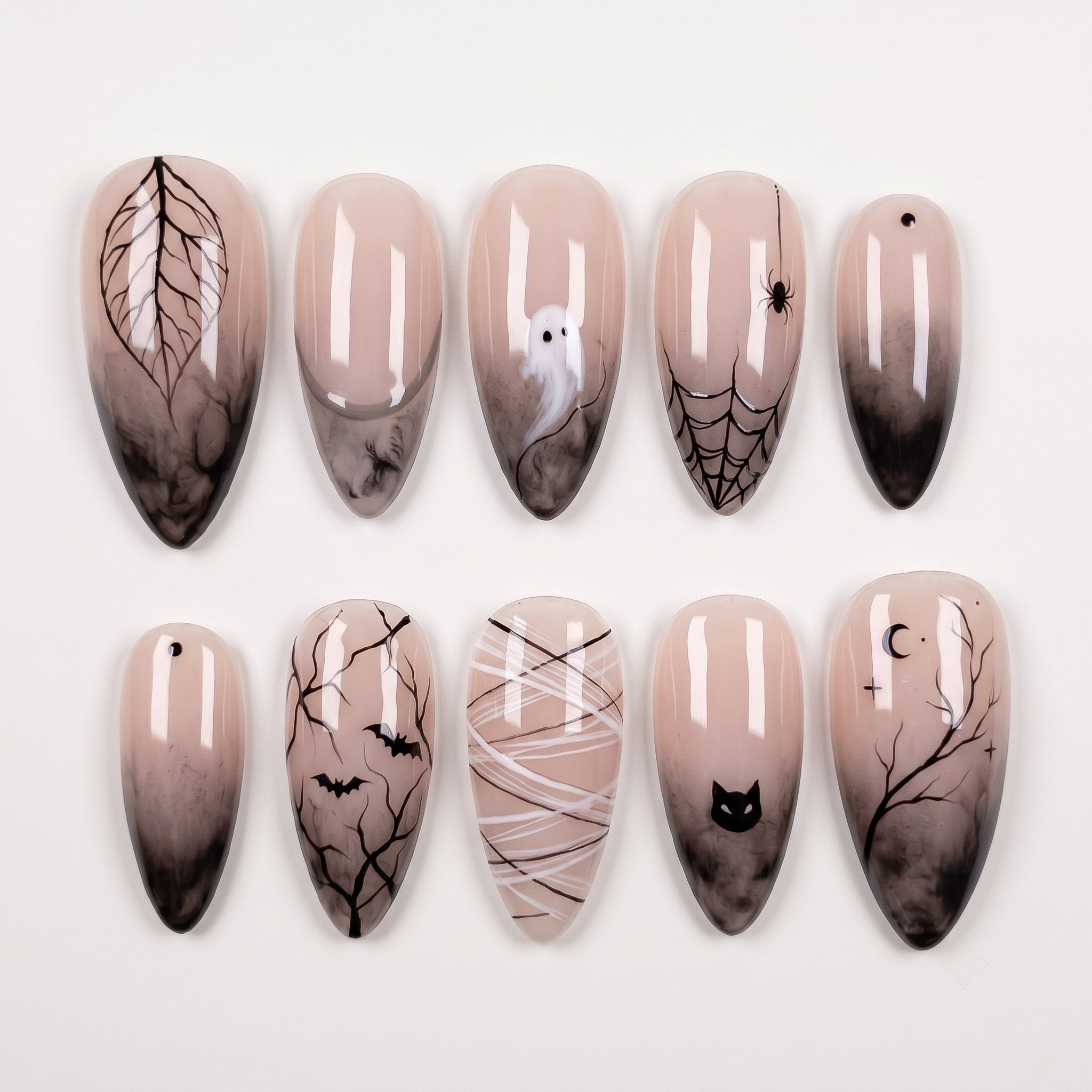 A set of spooky Halloween-themed press-on nails featuring black smoke gradients, ghosts, spider webs, and bats on a nude base.