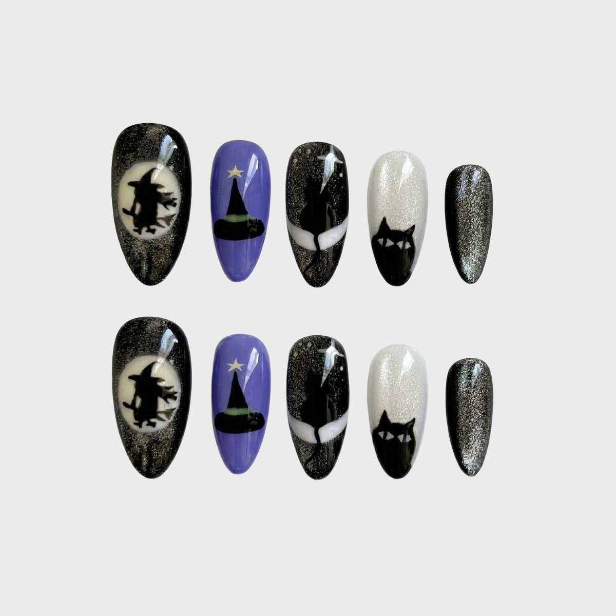 A set of Halloween press-on nails featuring witch, cat, and moon motifs in black, purple, and white glitter.