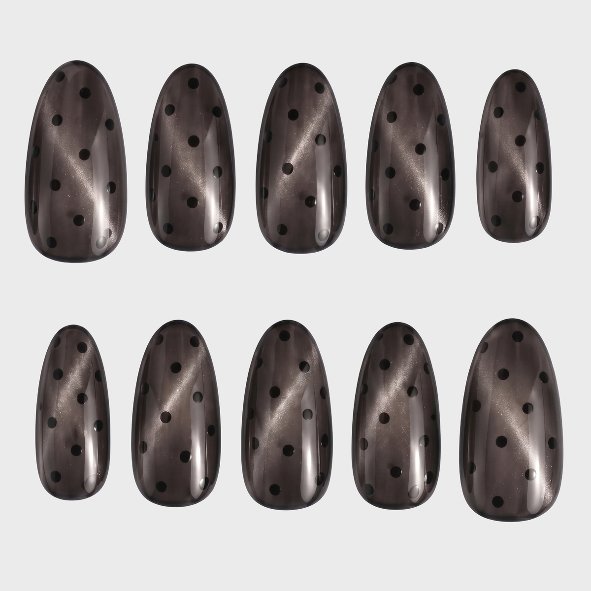A set of almond-shaped press-on nails featuring a translucent grey cat eye finish and black polka dot pattern.