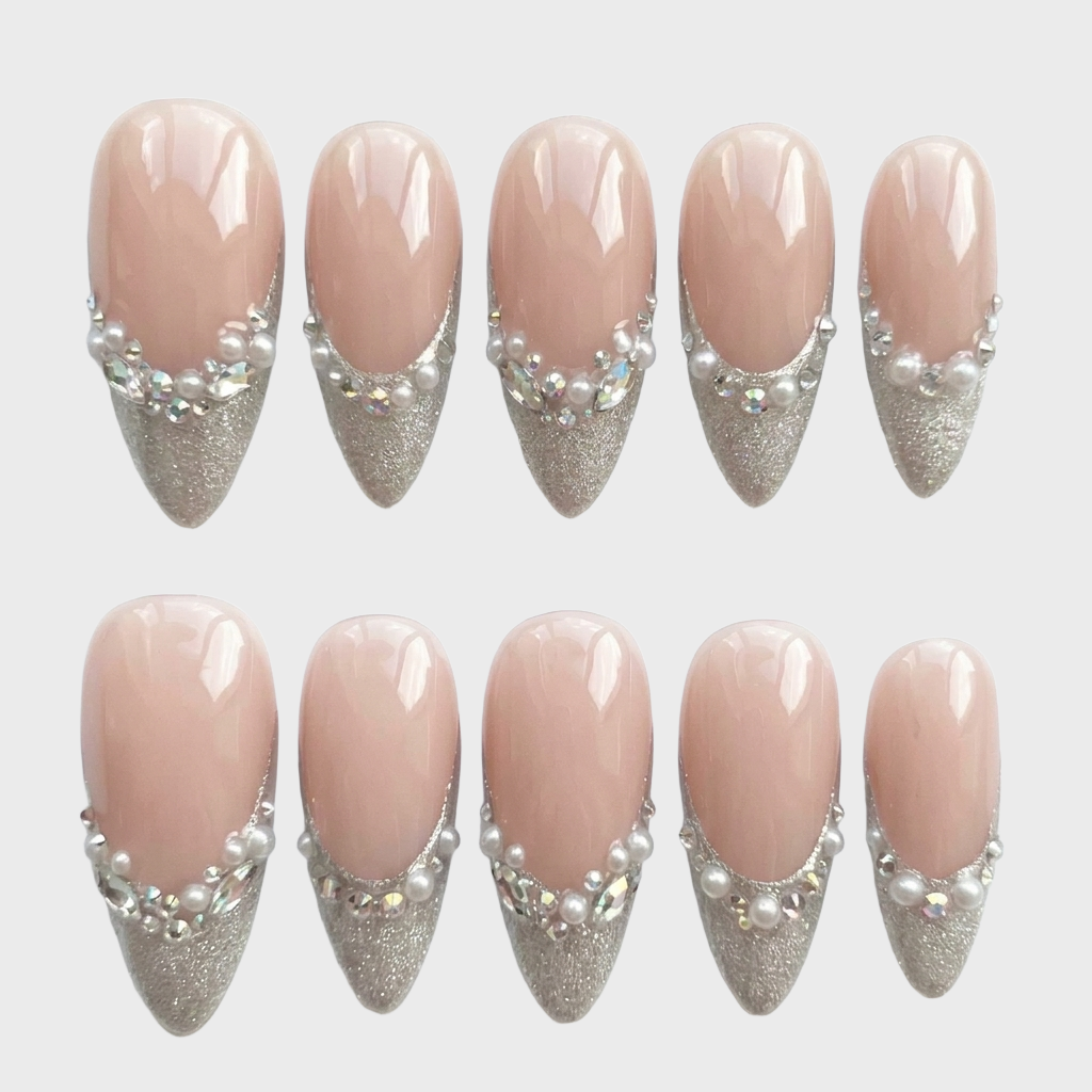 Nude press-on nails with silver glitter French tips, pearl and crystal accents.