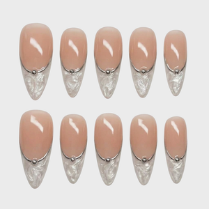 Nude press-on nails with white marbled French tips and silver stud accents.