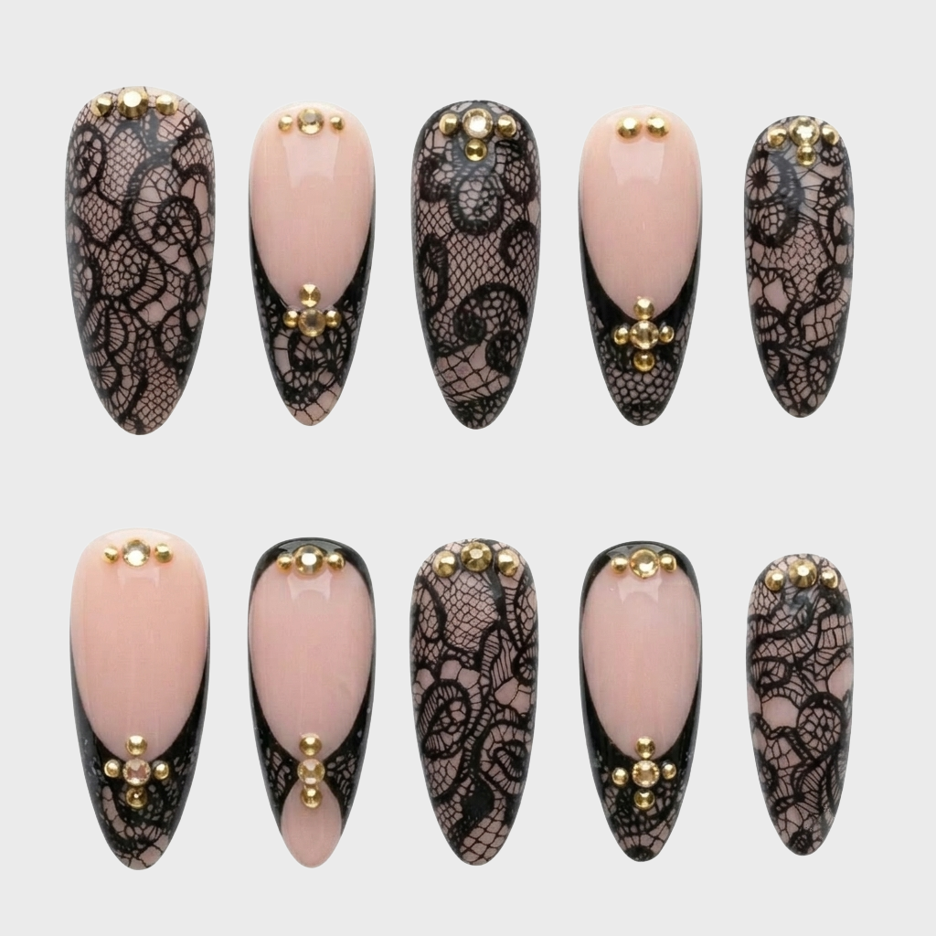 A set of press-on nails featuring black lace patterns, nude French tips, and gold stud embellishments.