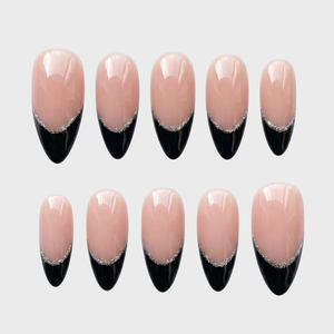 Almond shaped press-on nails featuring a nude base with black french tips and silver glitter accents.