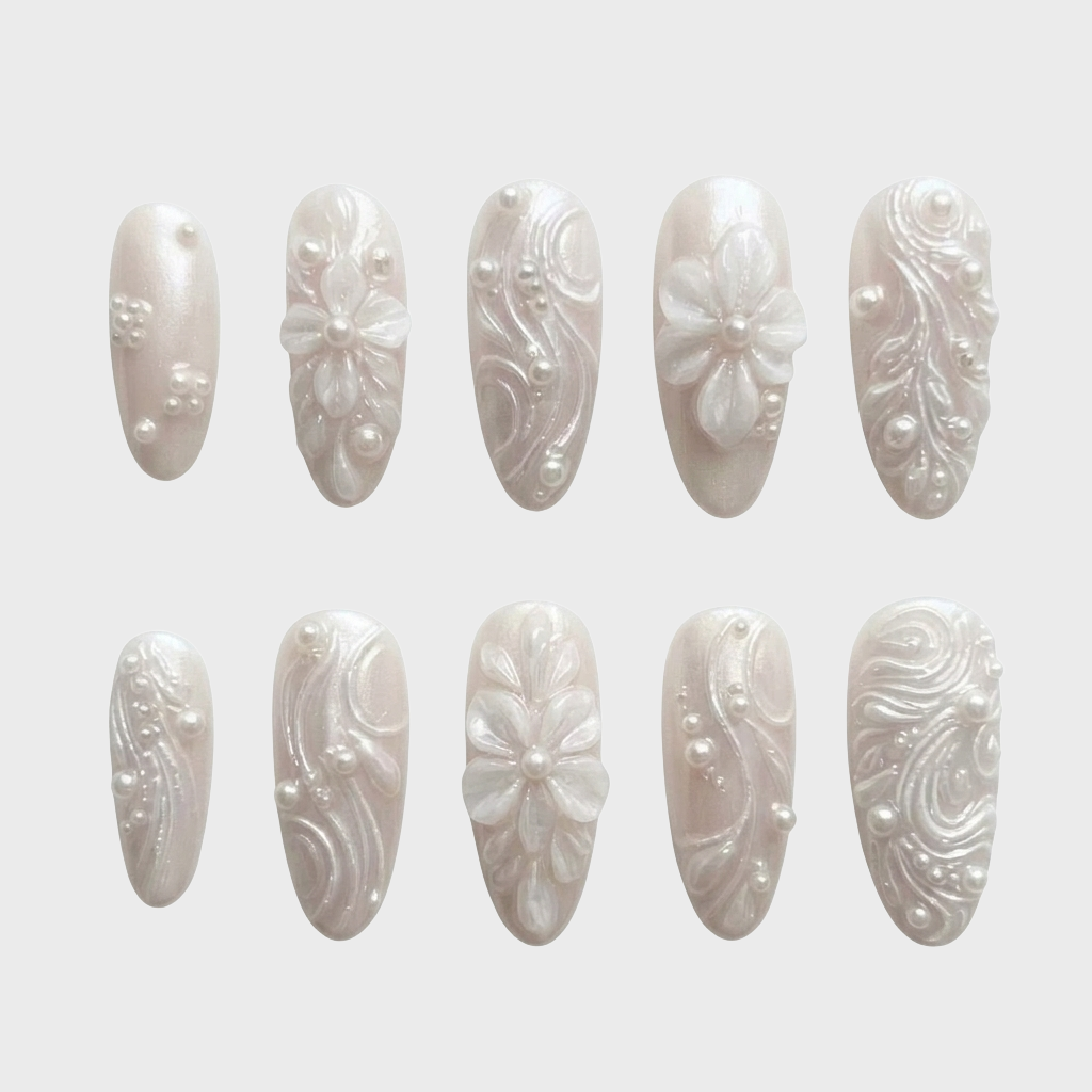 A set of pearlescent white press-on nails featuring 3D floral designs, raised swirls, and pearl embellishments.