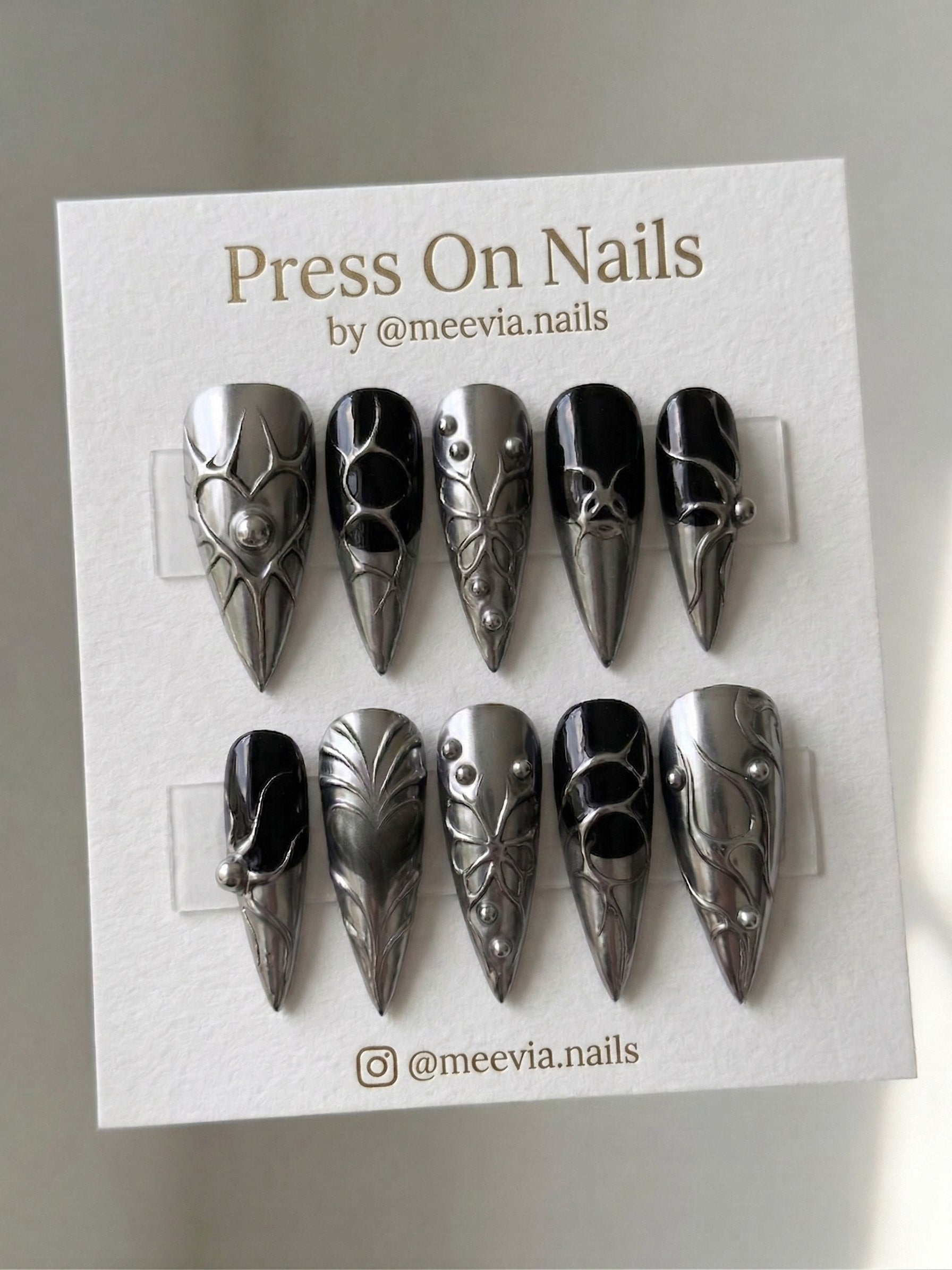 Stiletto-shaped silver chrome and black press-on nail set with 3D metallic liquid-metal art
