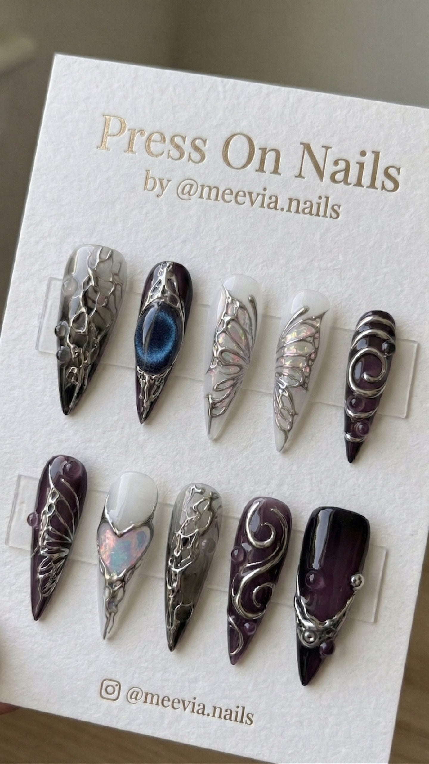 Long stiletto press-on nails with purple jelly base, 3D silver molten art, and iridescent butterfly wings.