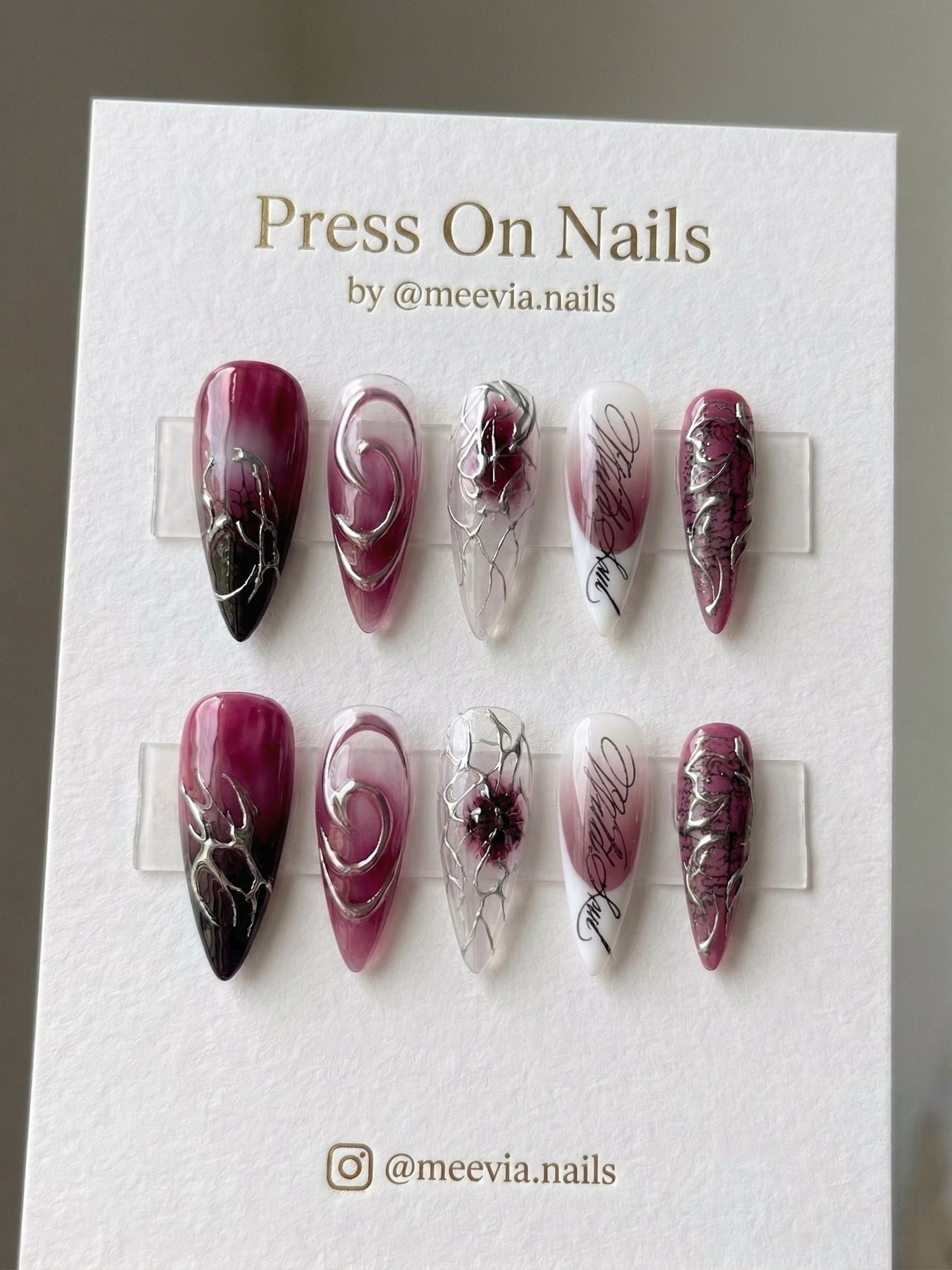 Long stiletto press-on nail set featuring deep wine ombre, black script, and 3D silver chrome accents.