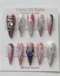Long stiletto pink chrome press-on nails with 3D silver liquid metal art and iridescent heart charm.