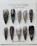 Long stiletto-shaped press-on nail set with silver chrome roses, navy cat eye shimmer, and 3D metallic accents
