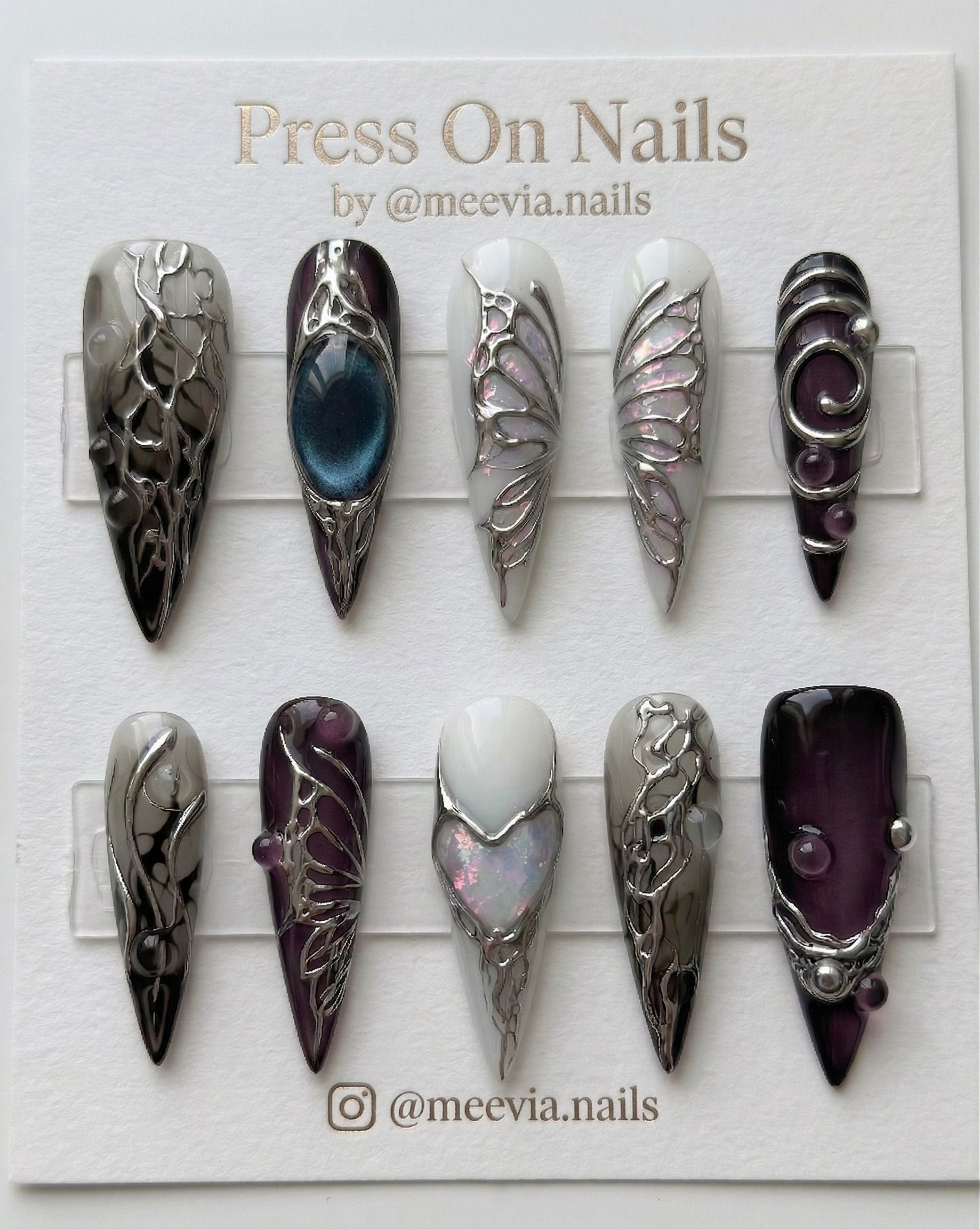 Long stiletto-shaped press-on nail set with silver chrome roses, navy cat eye shimmer, and 3D metallic accents