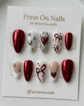 Almond-shaped red chrome press-on nails with 3D silver hearts and red bow designs