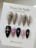 Stiletto-shaped gothic press-on nail set featuring silver cross and star charms in black and taupe colors.