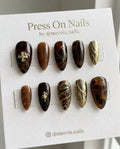 Almond-shaped tortoiseshell press-on nail set with gold 3D accents and cross charms