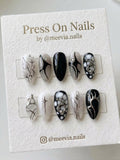 Almond-shaped gothic press-on nail set with black and white abstract art and 3D silver chrome accents.