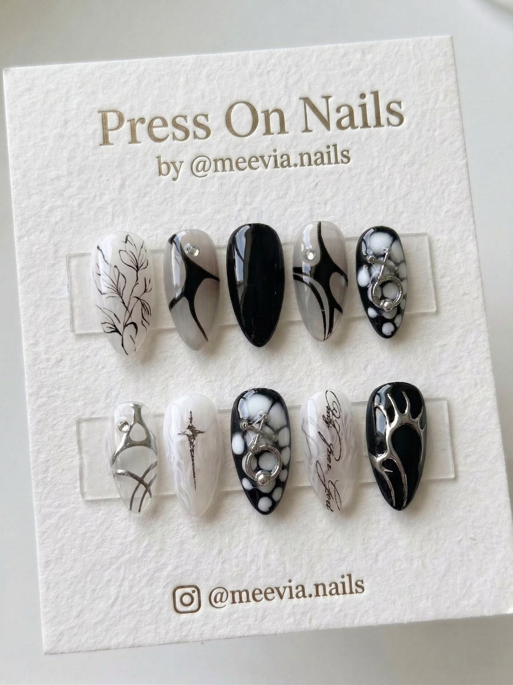Almond-shaped gothic press-on nail set with black and white abstract art and 3D silver chrome accents.