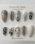 Stiletto-shaped gothic press-on nail set with silver chrome crosses, 3D bows, and script art