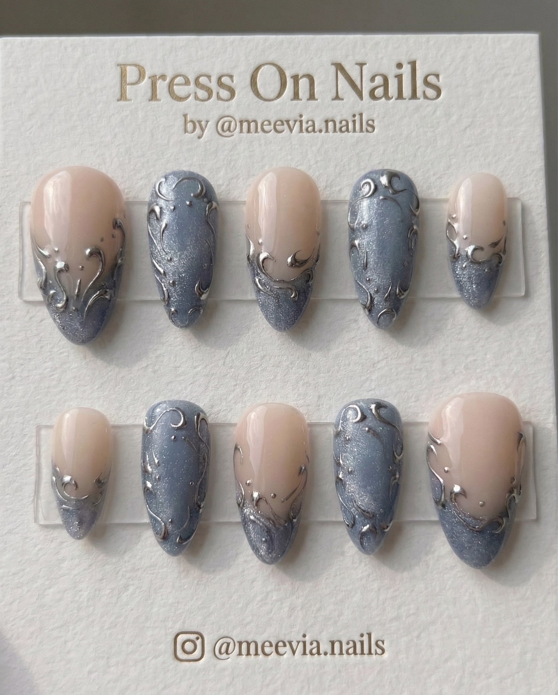 Almond-shaped press-on nail set with silver 3D filigree and blue shimmer tips