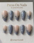 Almond shaped press on nails with blue shimmer tips and silver 3D swirl motifs