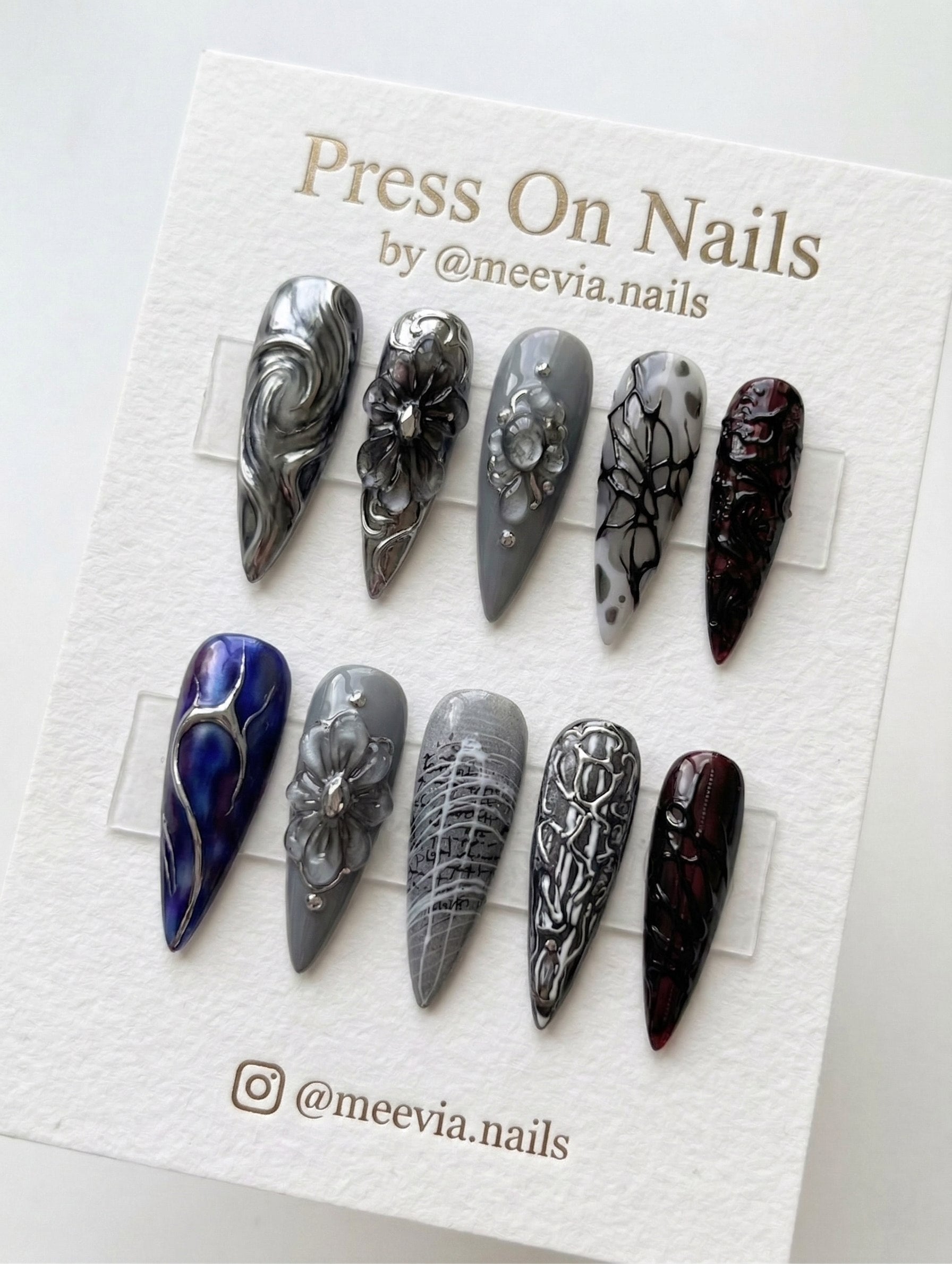 Stiletto-shaped gothic press-on nails with chrome 3D floral art and deep burgundy textures