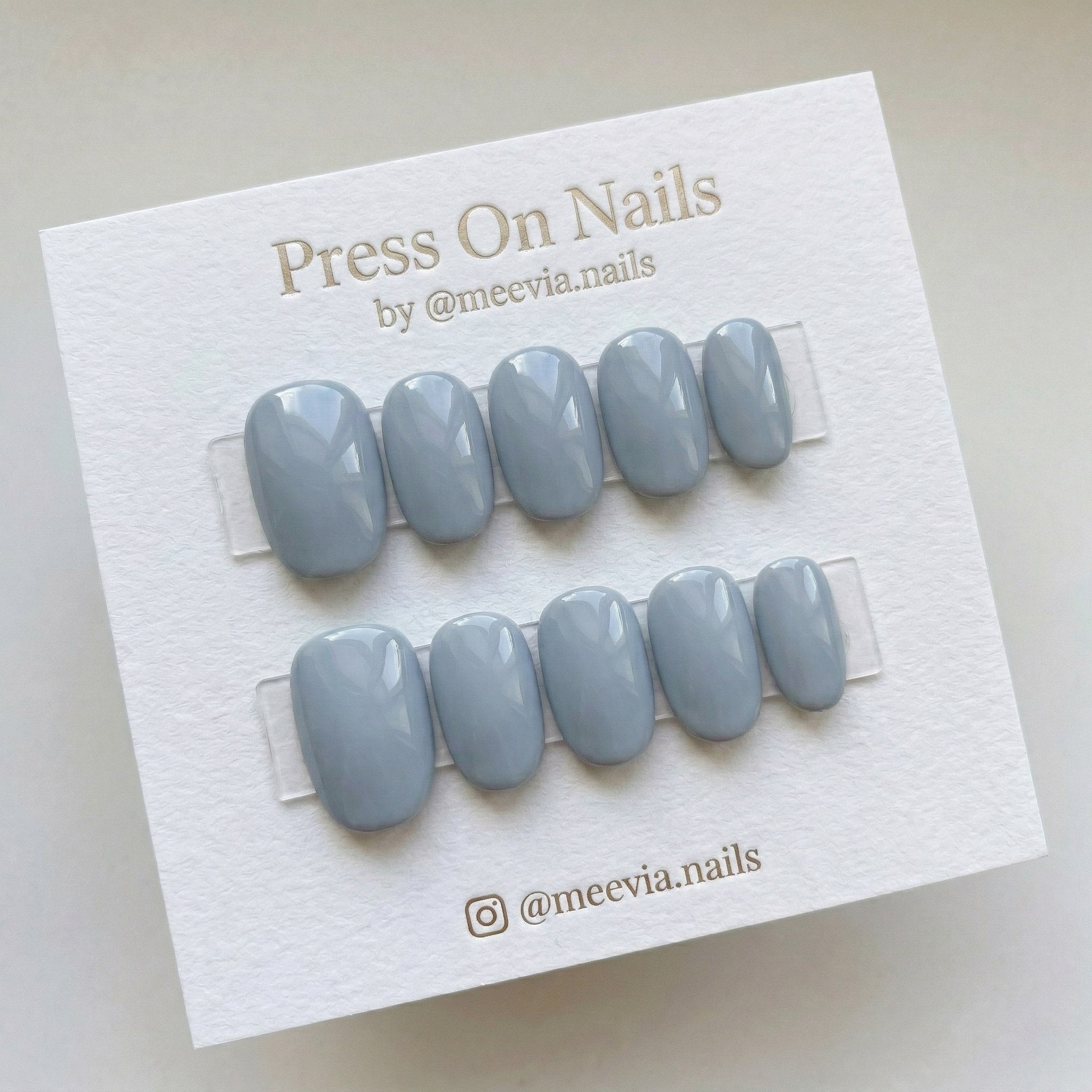 Oval-shaped dusty blue press-on nails with a high-gloss finish