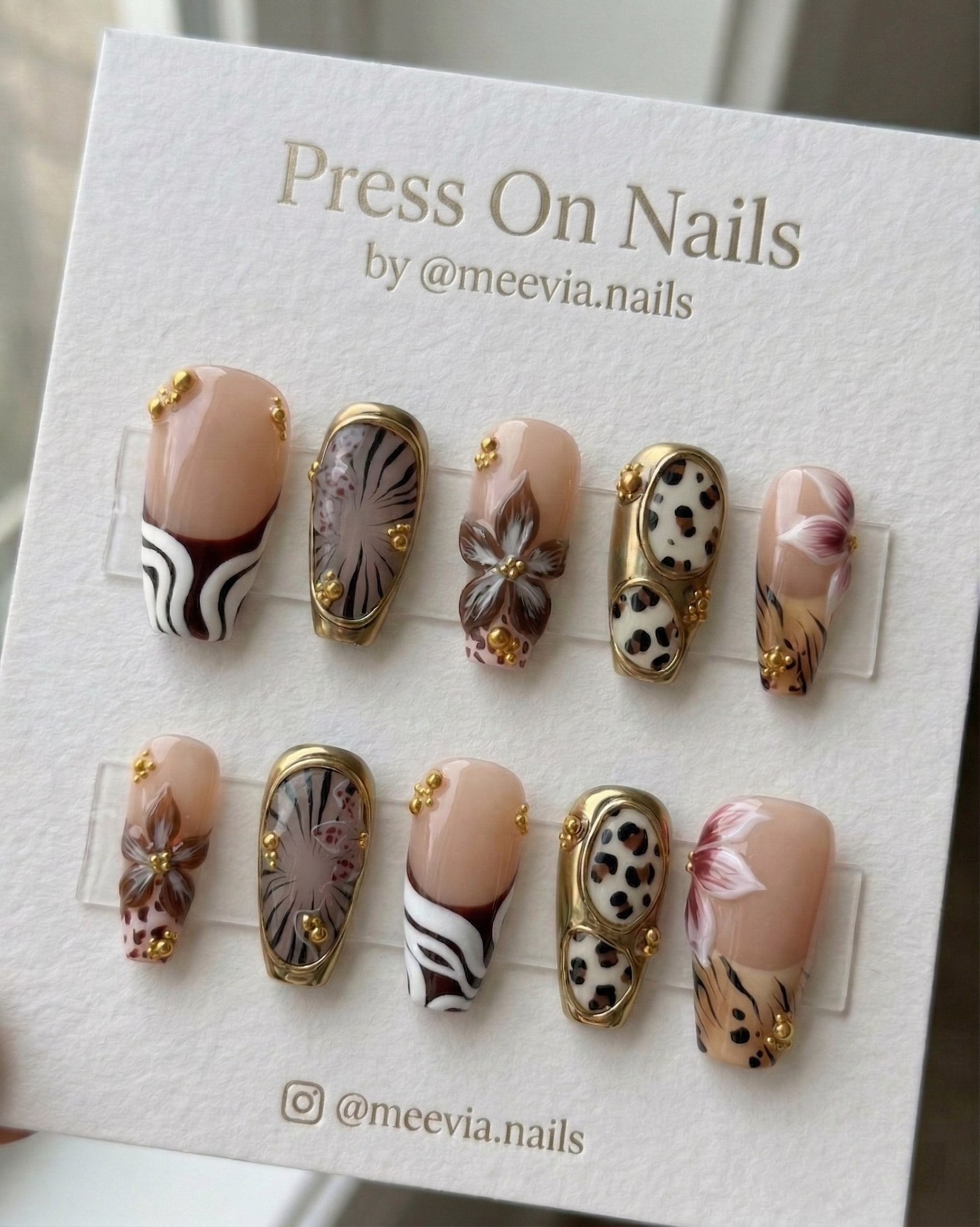Long coffin-shaped press-on nails with safari animal prints, 3D brown flowers, and gold chrome detailing.