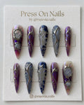 Long stiletto-shaped purple and blue press-on nails with 3D silver chrome liquid metal designs