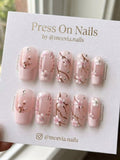 Square-shaped pink press-on nails with cherry blossom floral art and rhinestone accents