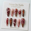Stiletto-shaped red and amber press-on nail set with 3D floral art and gold rose charms
