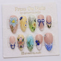 Almond-shaped press-on nail set with 3D floral art, butterflies, and blue bows