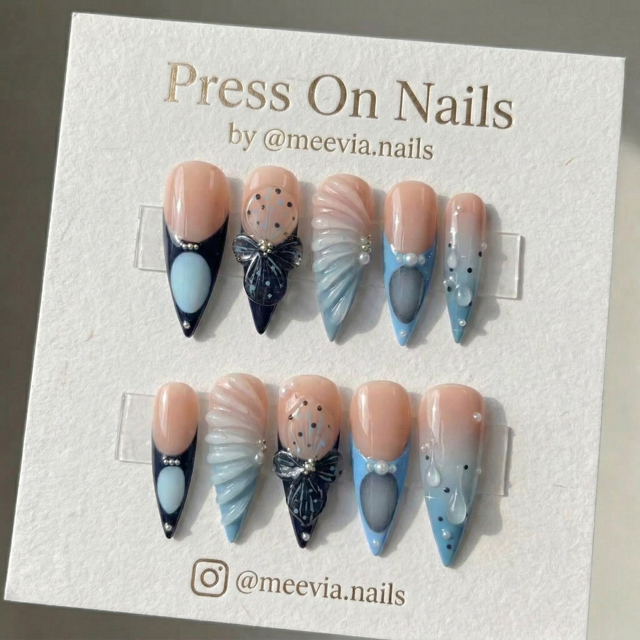 Stiletto-shaped blue press-on nail set with 3D butterfly motifs and textured shell designs