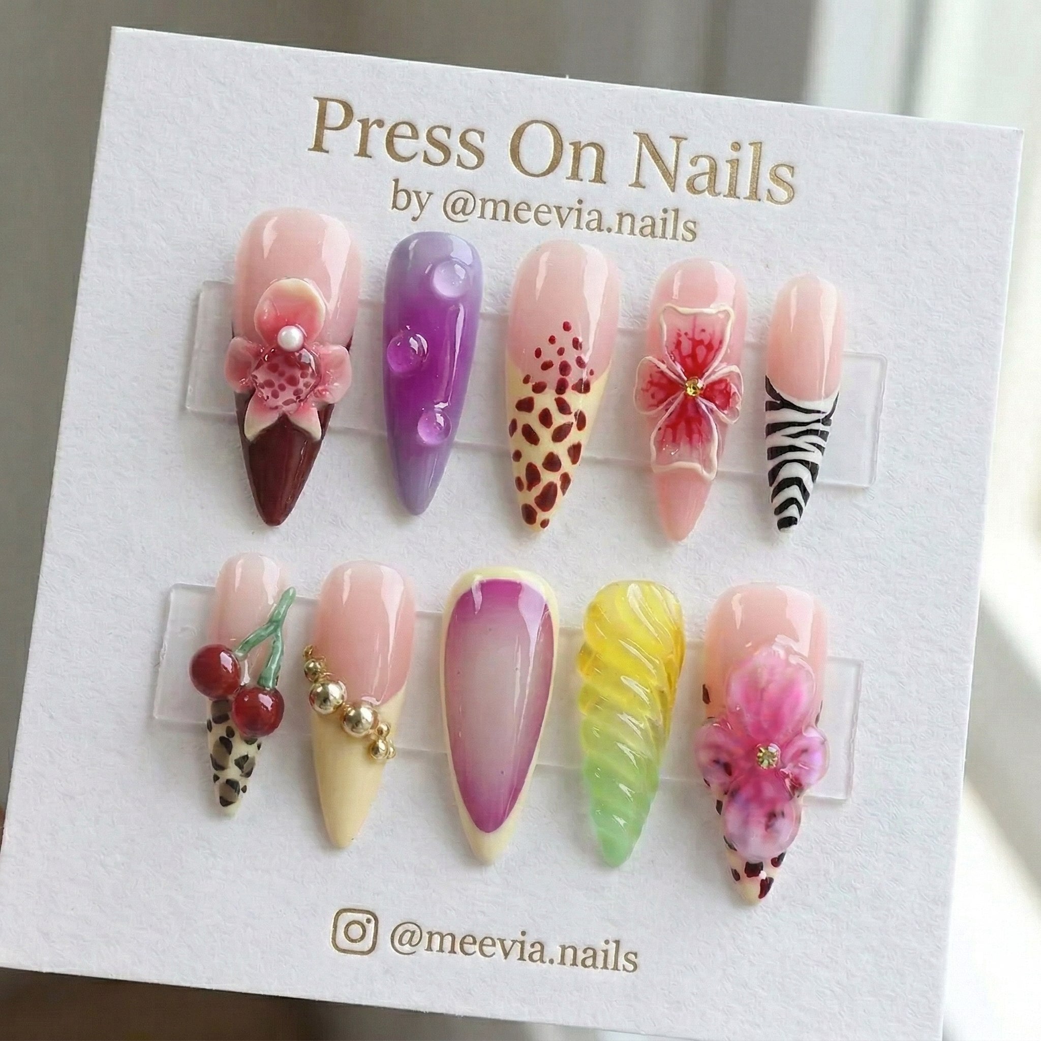 Stiletto-shaped press-on nails with 3D flowers, animal prints, and jelly droplets in a colorful artistic nail set.