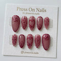 Almond-shaped mauve press-on nails with 3D metallic red heart and scroll designs