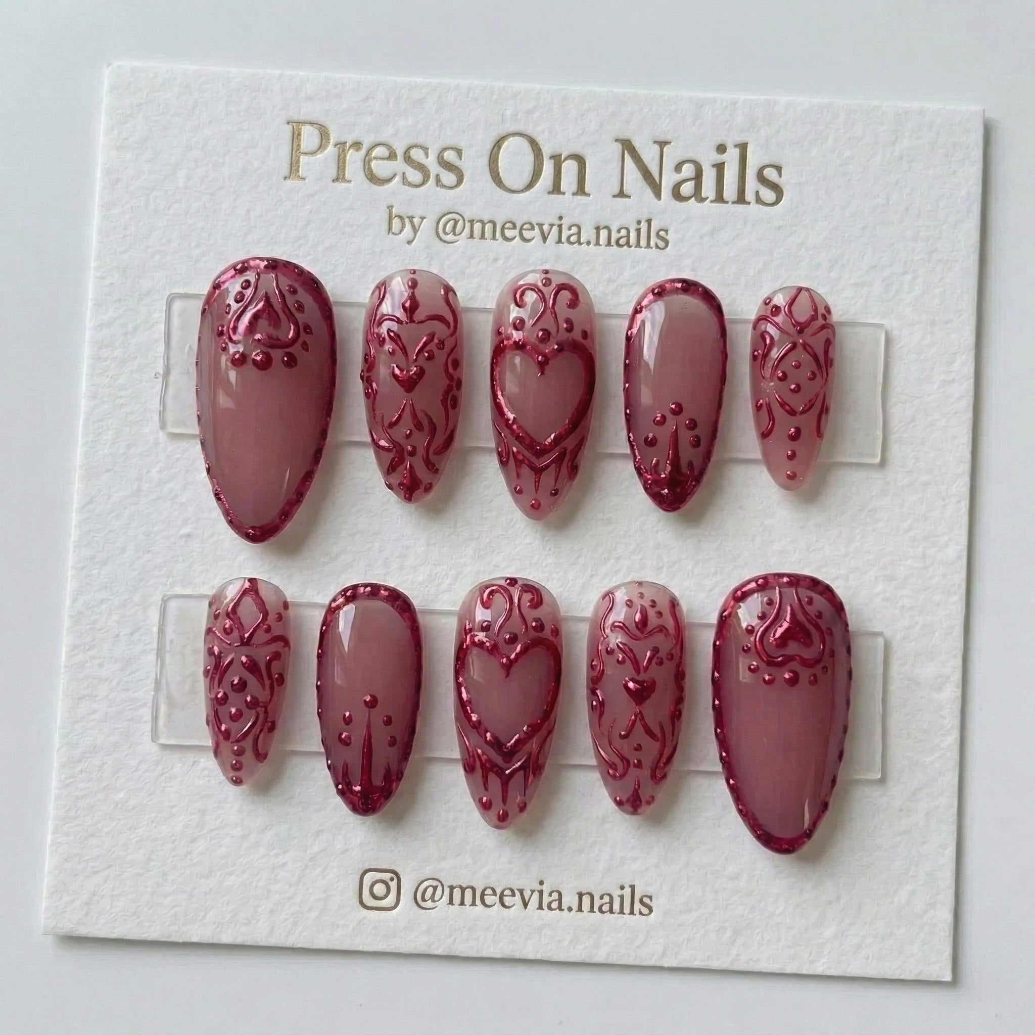 Almond-shaped mauve press-on nails with 3D metallic red heart and scroll designs