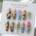 Long square ocean-themed press-on nails with 3D seashells, pearls, and mermaid-inspired glitter art.