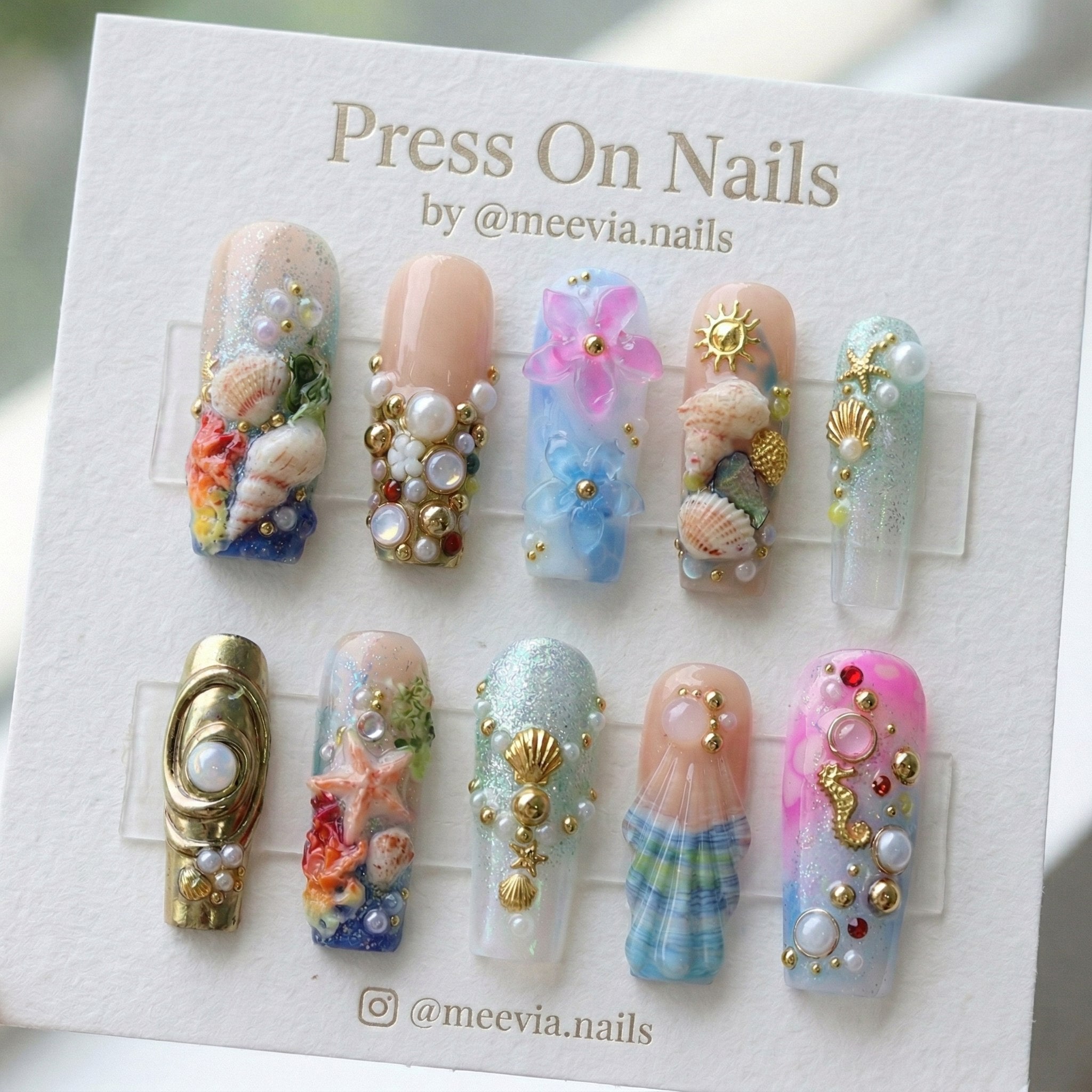 Long square ocean-themed press-on nails with 3D seashells, pearls, and mermaid-inspired glitter art.