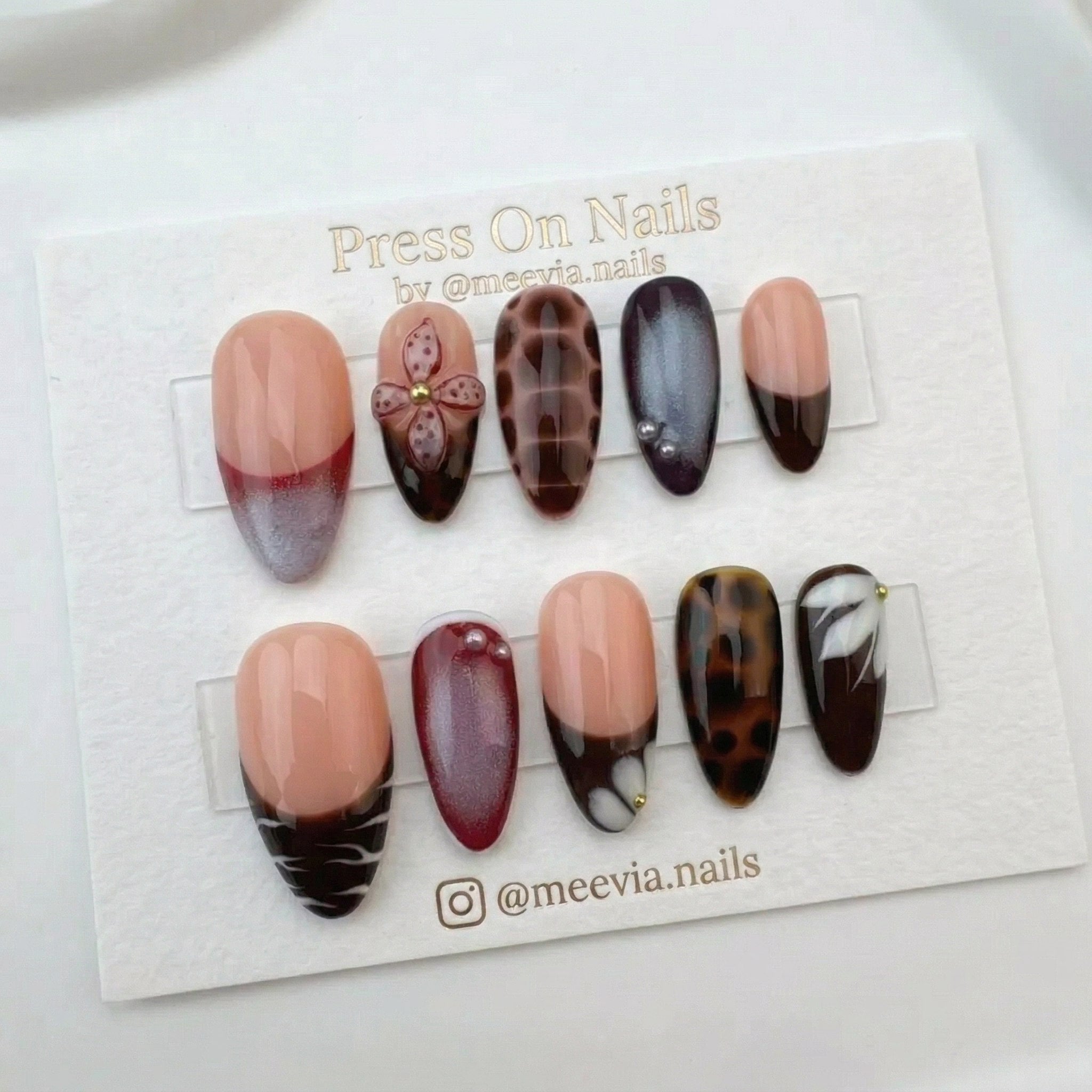 Almond-shaped press-on nail set with 3D burgundy flowers, tortoise shell patterns, and French tips.