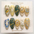 Almond-shaped press on nails featuring 3D lemon, tea cup, and floral art with gold accents