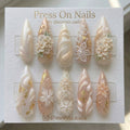 Stiletto-shaped pearl shimmer press-on nail set with 3D floral art and gold foil accents