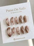 Oval-shaped rose gold floral press-on nail set with metallic shimmer finish