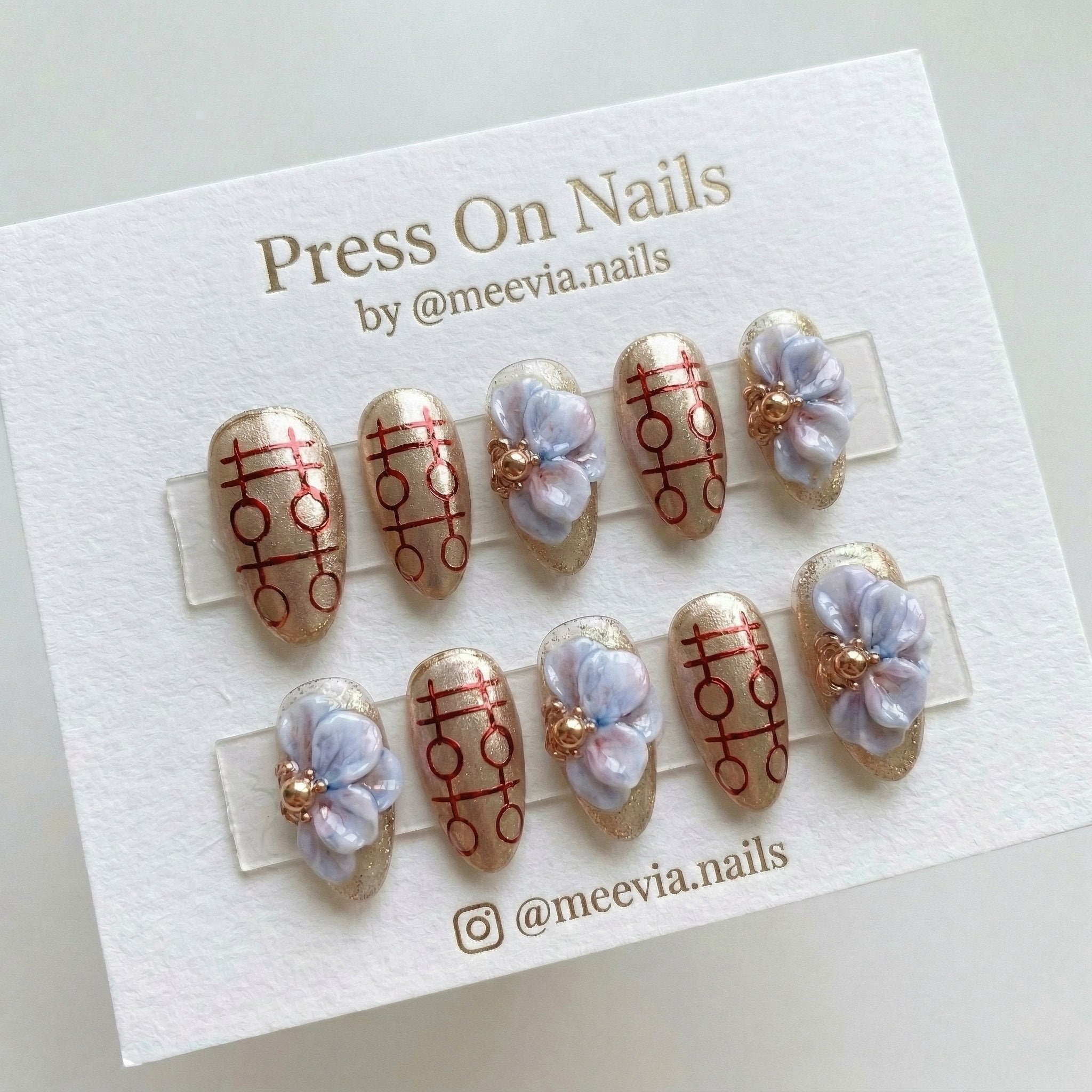 Almond-shaped gold metallic press-on nails with 3D marbleized flowers and red double happiness symbols